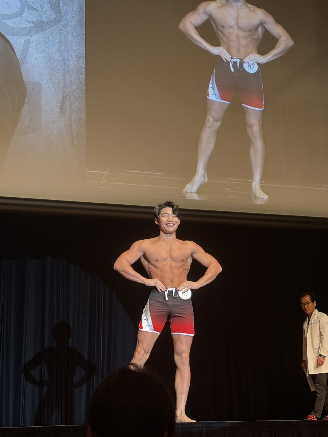フィジーク大会のステージで笑顔でポーズをとる加藤寛人
